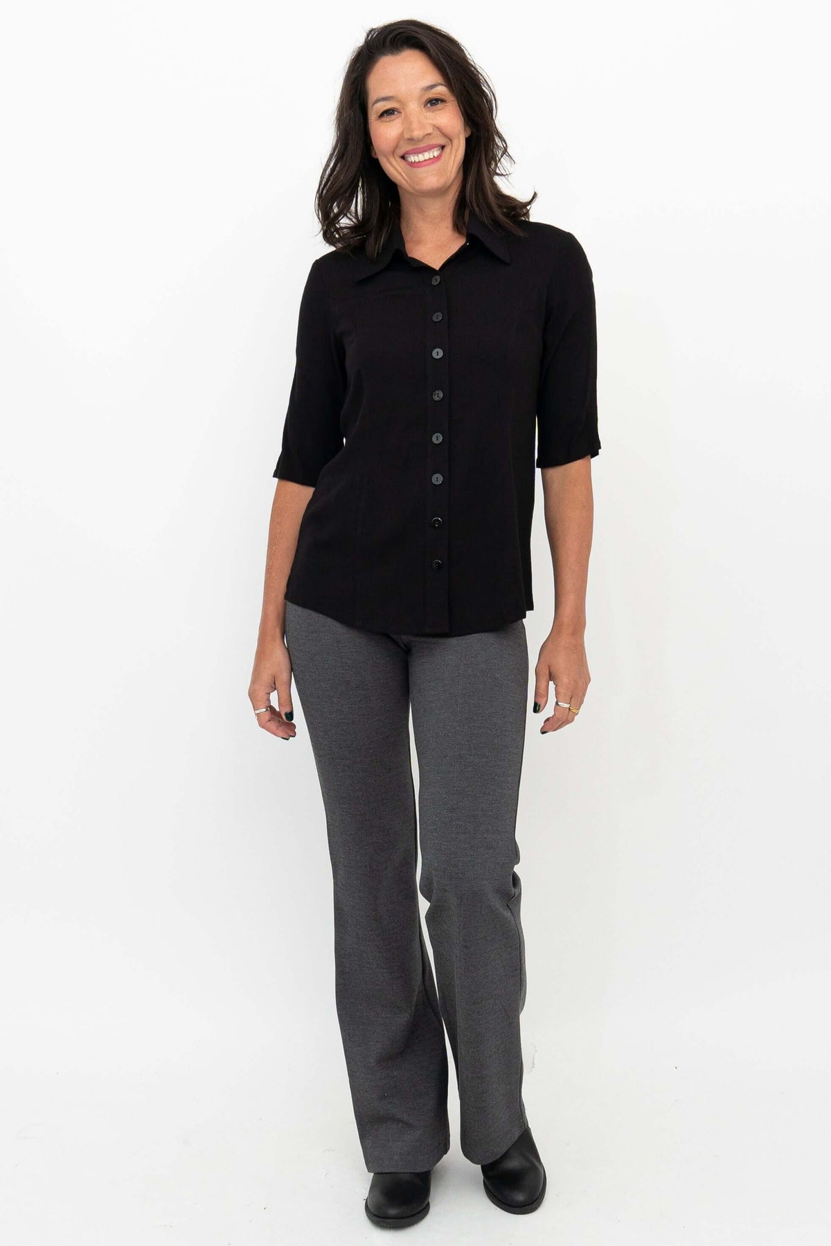 Woman smiling, wearing granite grey pants and black shirt, front view