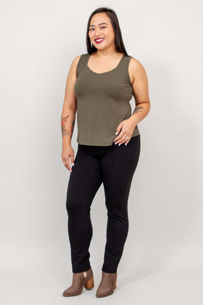 Model posing in olive Ritzy tank top and black pants, angled view