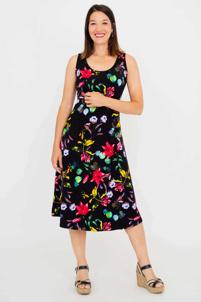 Woman modeling a black floral sleeveless tank dress, standing with hand on hip