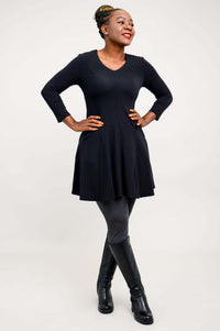 Model looking to the side, smiling and posing in a black tunic dress