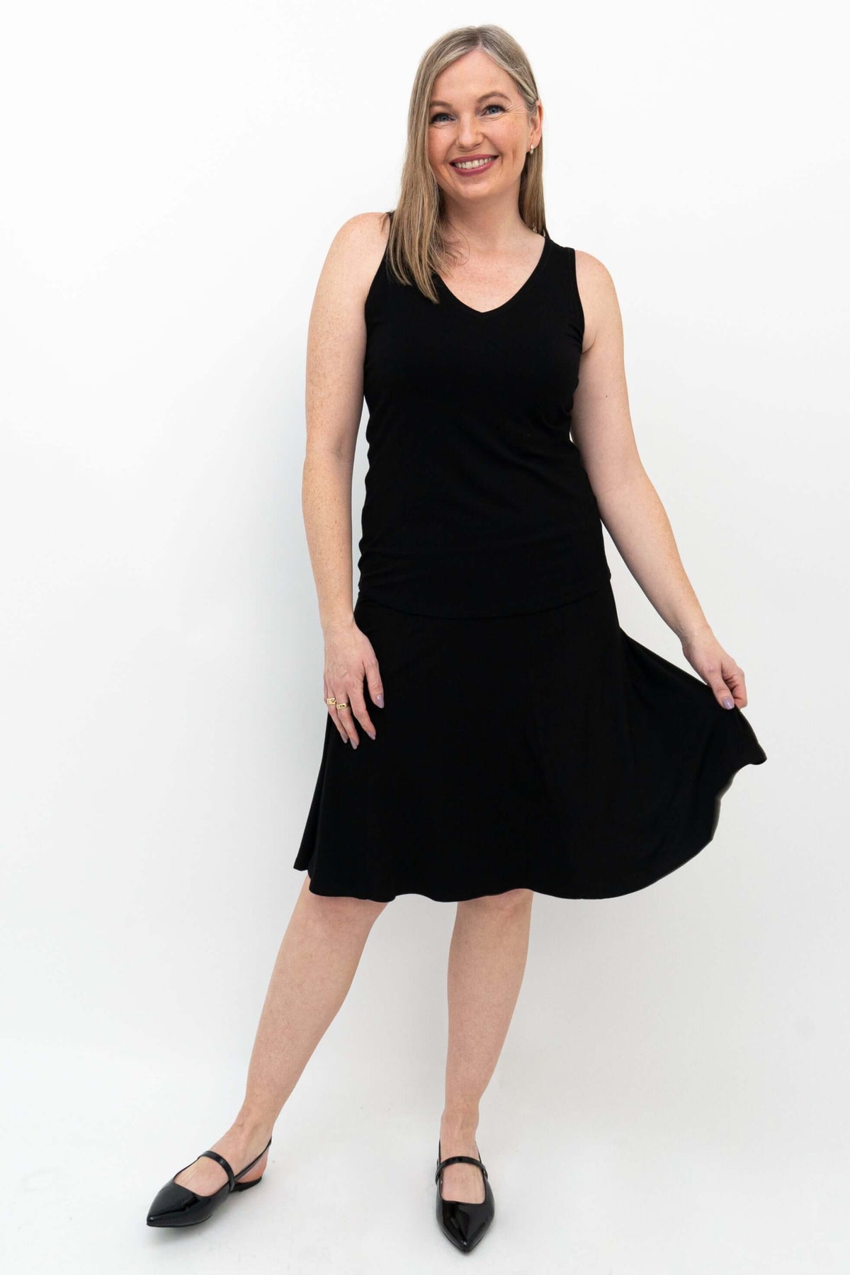 Model wearing Aly fit and flare black skirt, holding out the hem