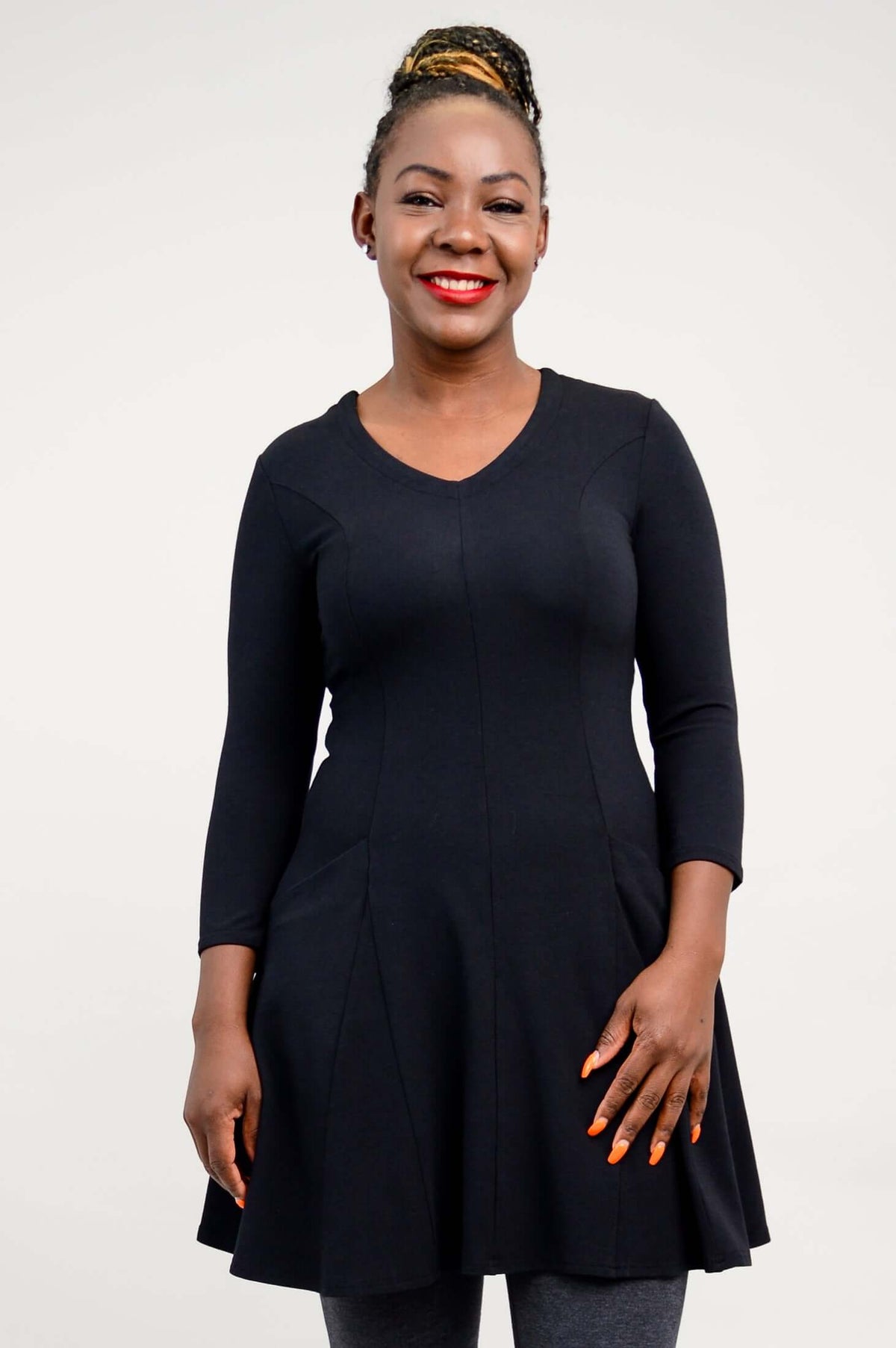 Model wearing a black tunic dress with three-quarter sleeves and a V-neckline