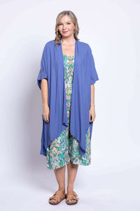 Model wearing a blue open cardigan over a green wide leg jumpsuit