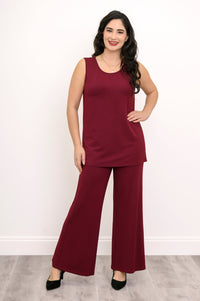 Full-length view of a woman walking in a burgundy sleeveless tank top and matching knit pants.