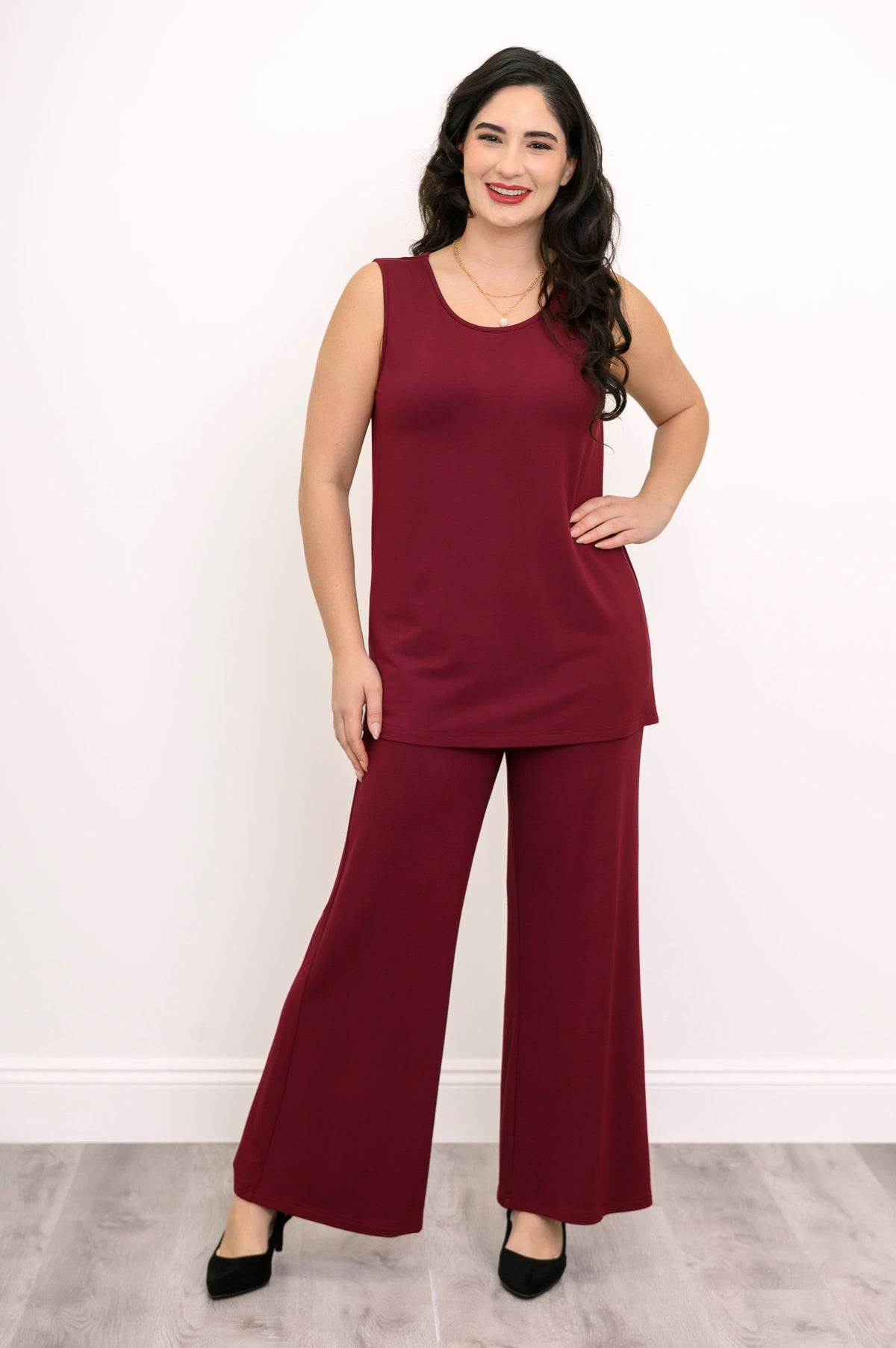 Full-length front view of a woman wearing a burgundy sleeveless knit tank top paired with matching wide-leg pants.