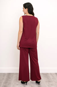 Back view of a female model wearing a red French Terry tank and red pants with black heels against a white background and grey floor