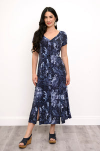 Full body view of woman wearing a dark blue floral print maxi dress, silver earrings, and sandals