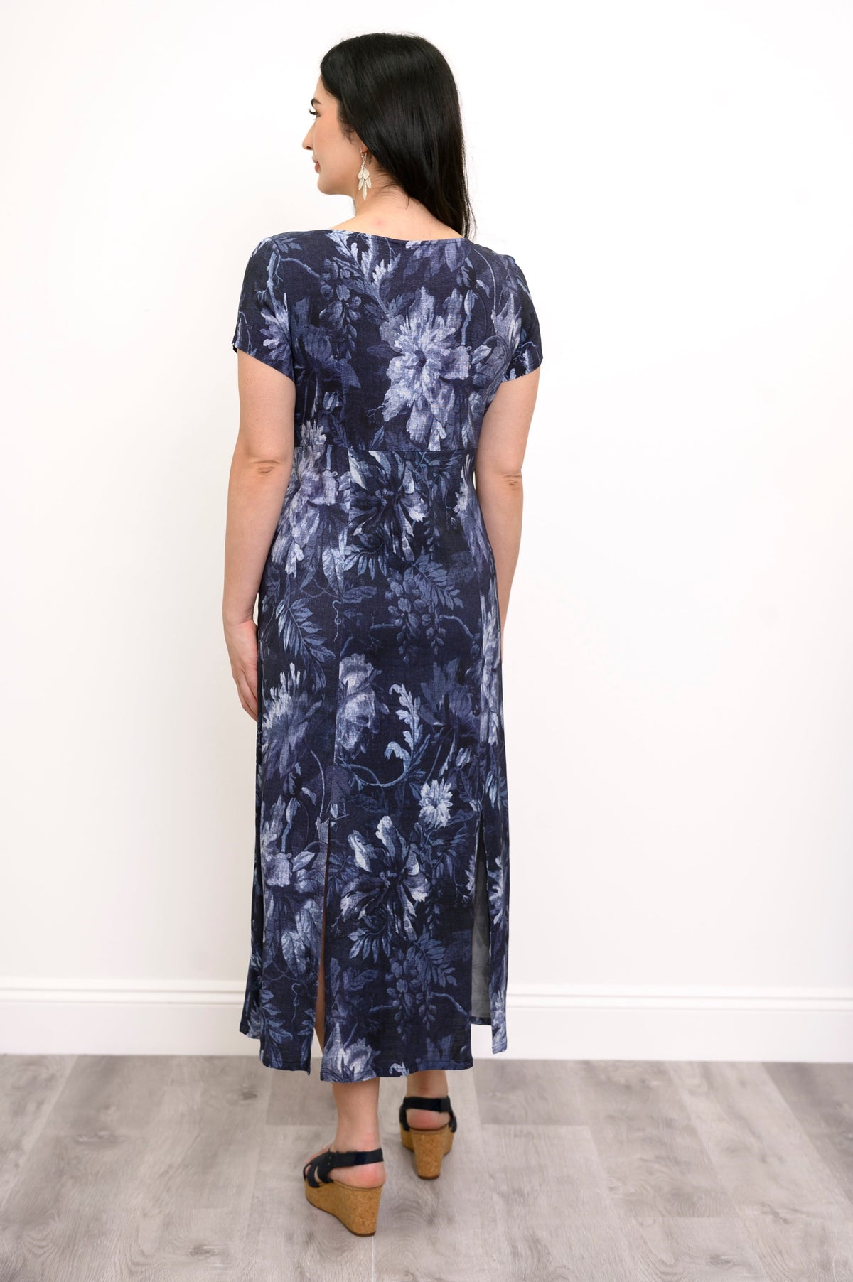 Full body back view of woman wearing a short sleeve dark navy floral print maxi dress and sandals