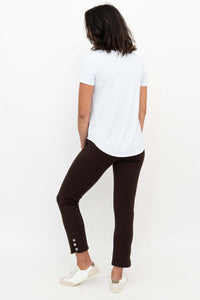 Model in Nadine Crop Pants in chocolate, white tee, shown from behind, highlighting ankle button detail