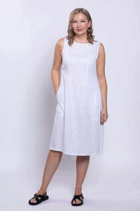 Woman standing in sleeveless white dress with vertical stripes and pockets