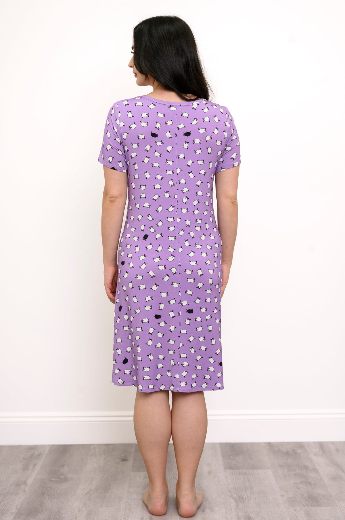 Back view of woman wearing a purple knee-length dress with a white and black sheep print