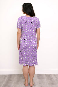Back view of woman wearing a purple knee-length dress with a white and black sheep print