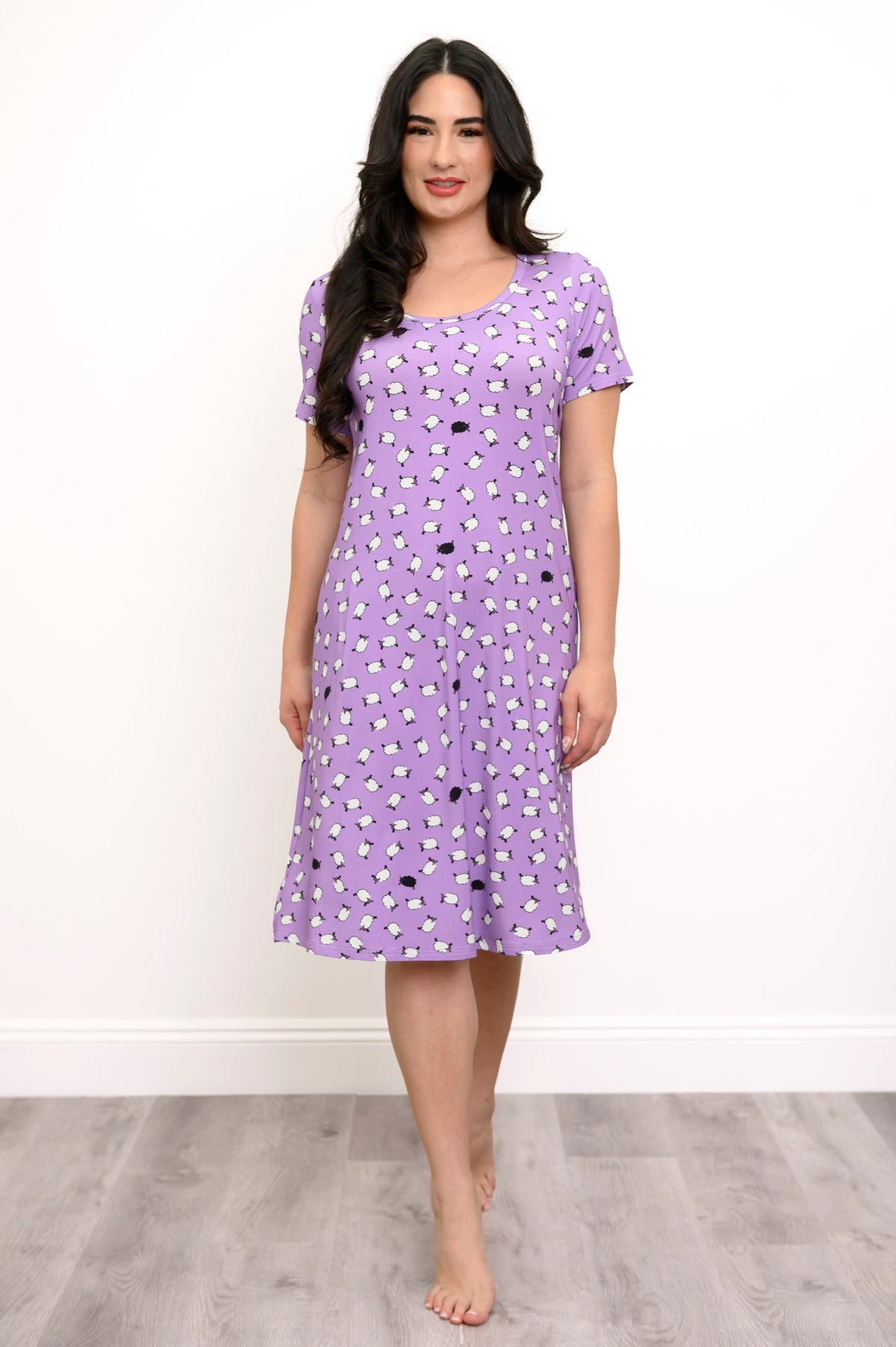Woman smiling while wearing a purple sheep print sleep dress against a white background