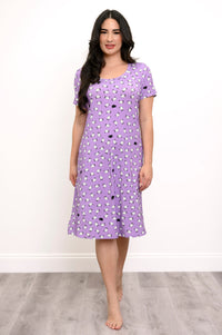 Woman smiling while wearing a purple sheep print sleep dress against a white background