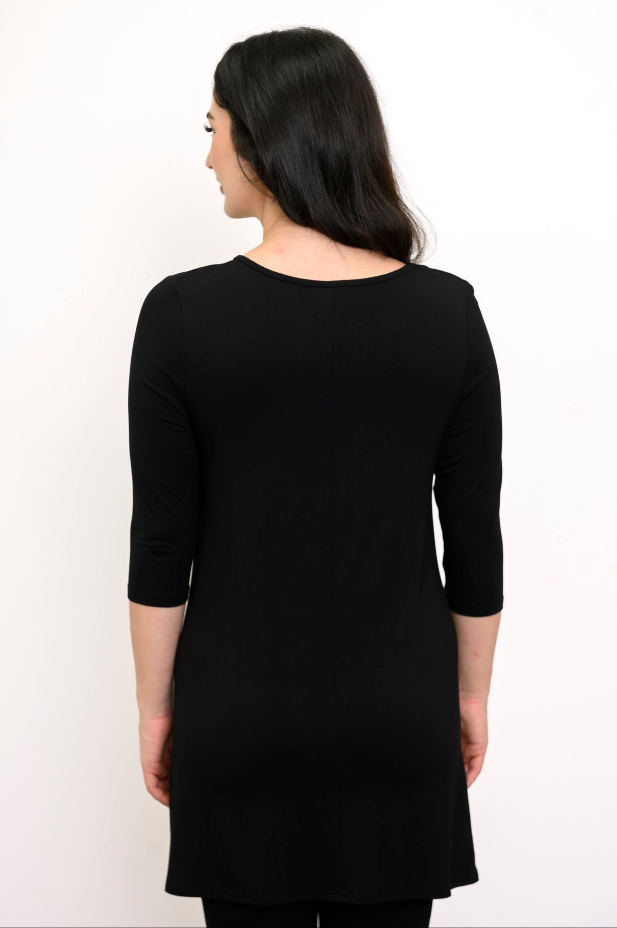 Back view of woman wearing plain black tunic with 3/4 sleeves