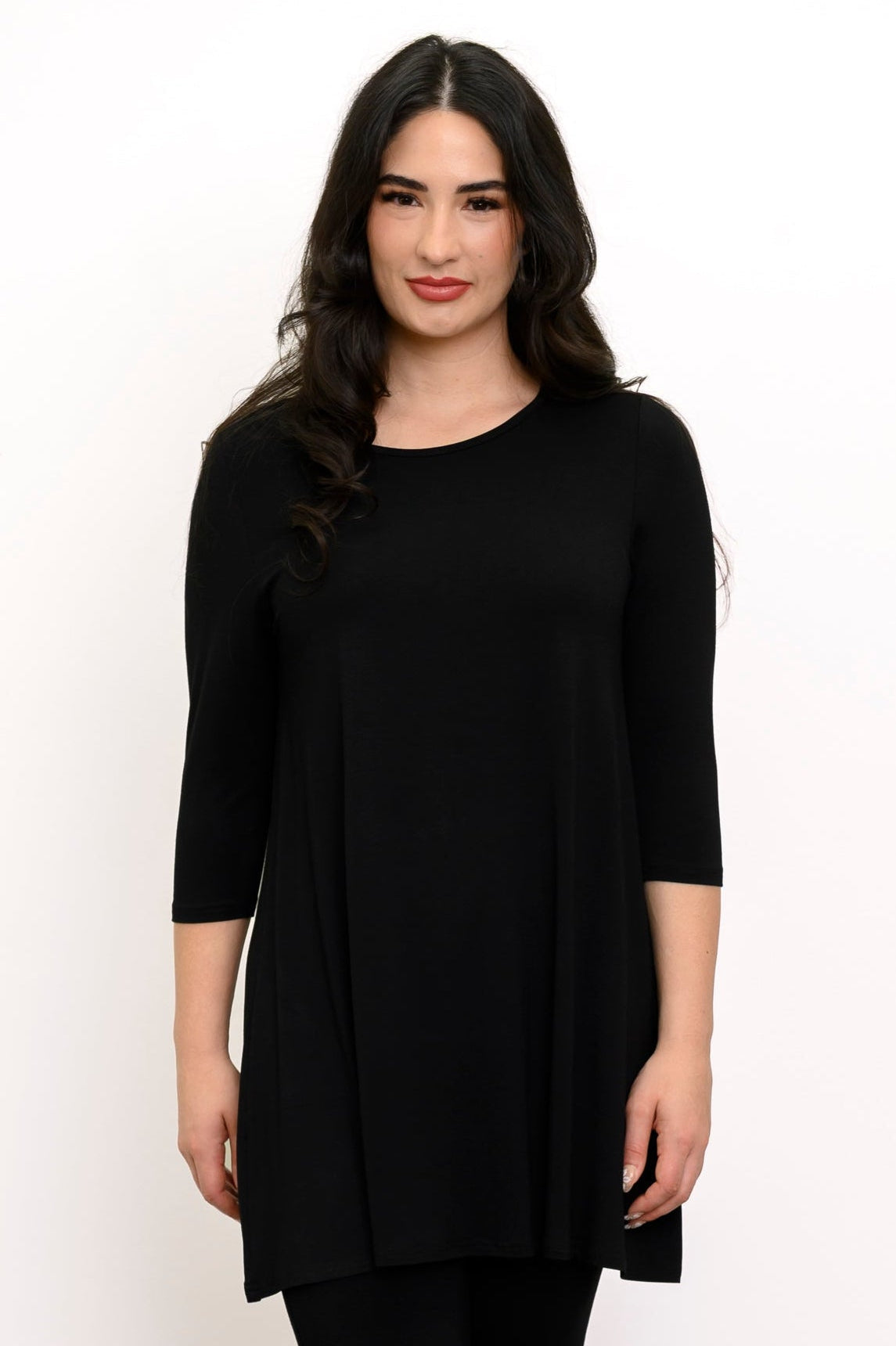 Woman wearing 3/4 sleeve black tunic and black pants against a white background