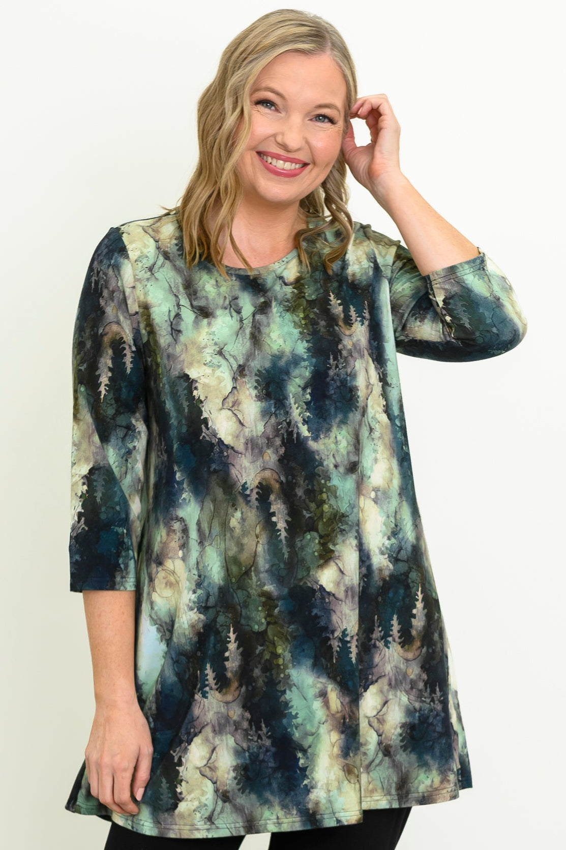 Front view of a female model wearing a blue-green watercolor forest print A-line tunic with 3/4 sleeves, against a white backdrop