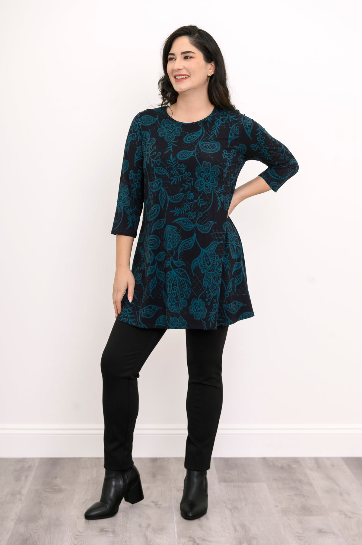Women's dark teal botanical print knit blouse with comfortable 3/4 sleeves, styled with black pants.