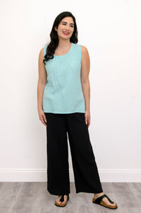 Woman wearing a light blue sleeveless top and black pants against a white background, front view