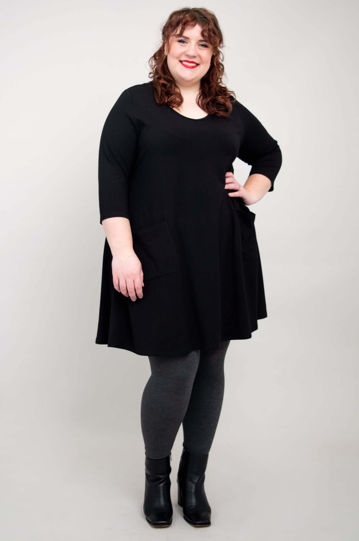 Plus size model posing with hand on hip in black A-line tunic dress