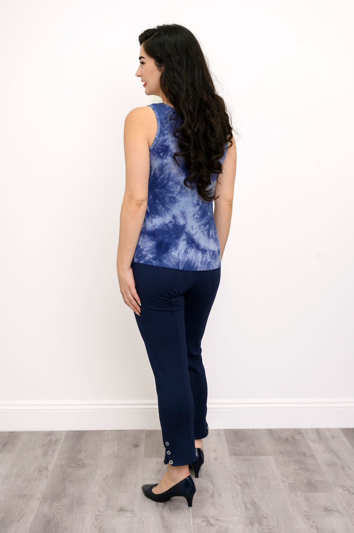 Back view of model in a blue tie-dye tank top and navy pants against a white background