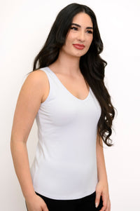 Woman angled slightly to the side while wearing a white full length sleeveless top
