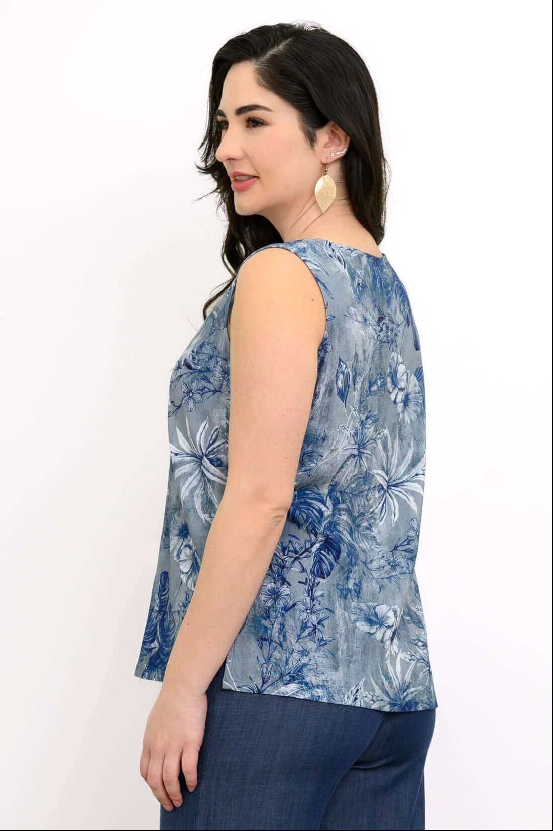Rear angled view of woman wearing a blue botanical sleeveless blouse and wide-leg pants