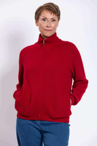 Woman wearing a red ribbed zip-up cardigan sweater with hands in pockets
