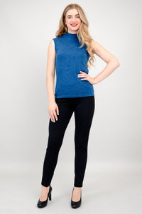 Full length front view of a model wearing a sleeveless blue merino wool sweater with tailored dark trousers.