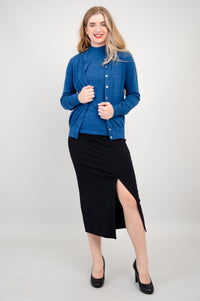 Woman modeling a blue button down sweater layered over a blue knit top and dark A-line skirt.