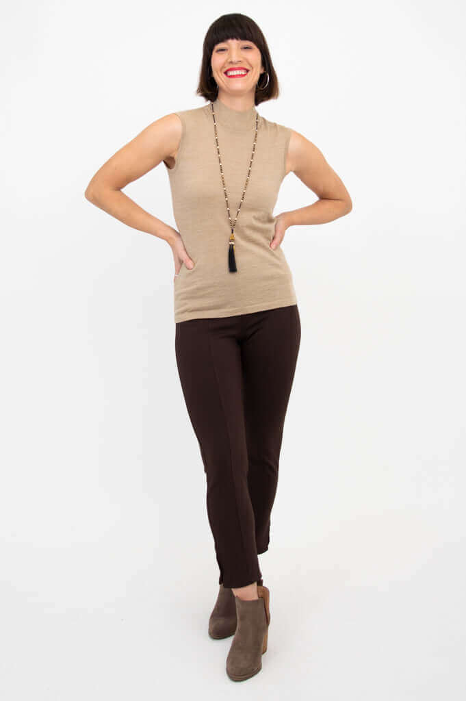 Full-length view of woman in tan sleeveless sweater and brown pants