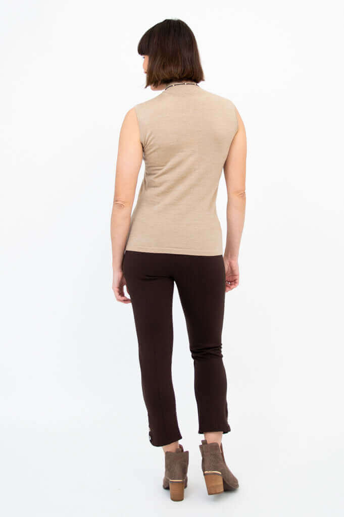Rear view of woman wearing a sleeveless tan sweater and brown pants