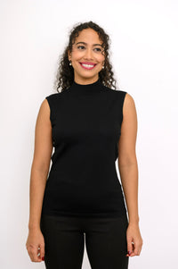 Woman standing against a white background modeling a fitted black sleeveless knit pullover sweater.