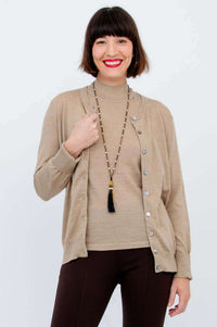 Woman layering a tan sleeveless mock neck sweater with a matching cardigan