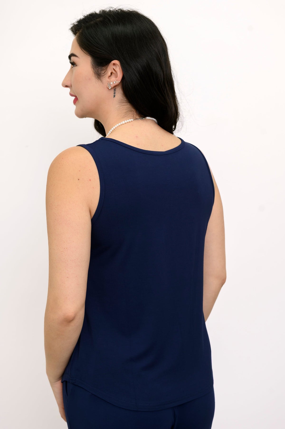 Woman wearing a navy blue sleeveless top and matching pants on a white background, back view