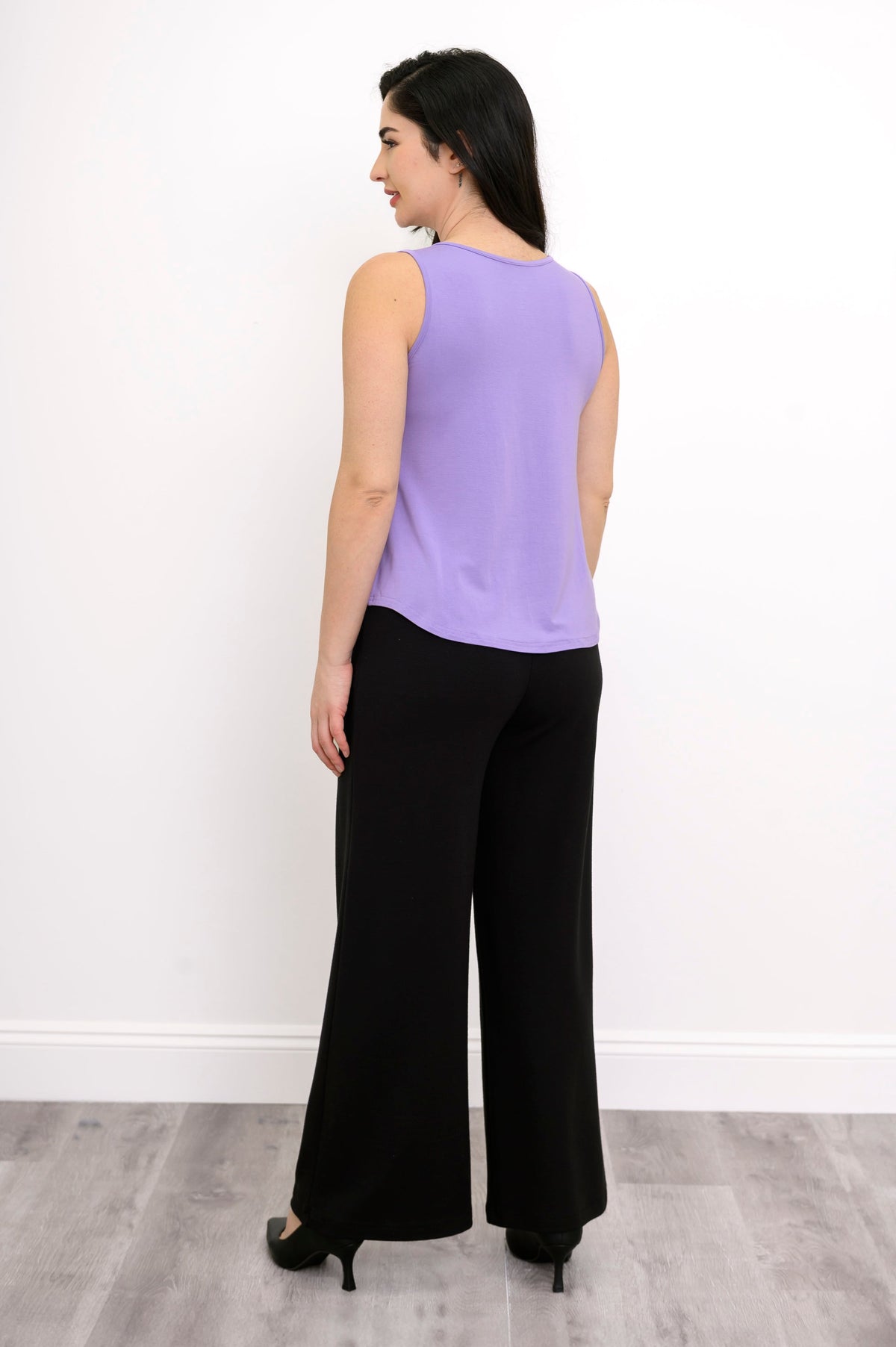 Back view of model in light lilac bamboo tank featuring relaxed fit, styled with black pants