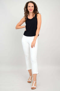 Woman posing in a black tank top and white pants with one hand on hip