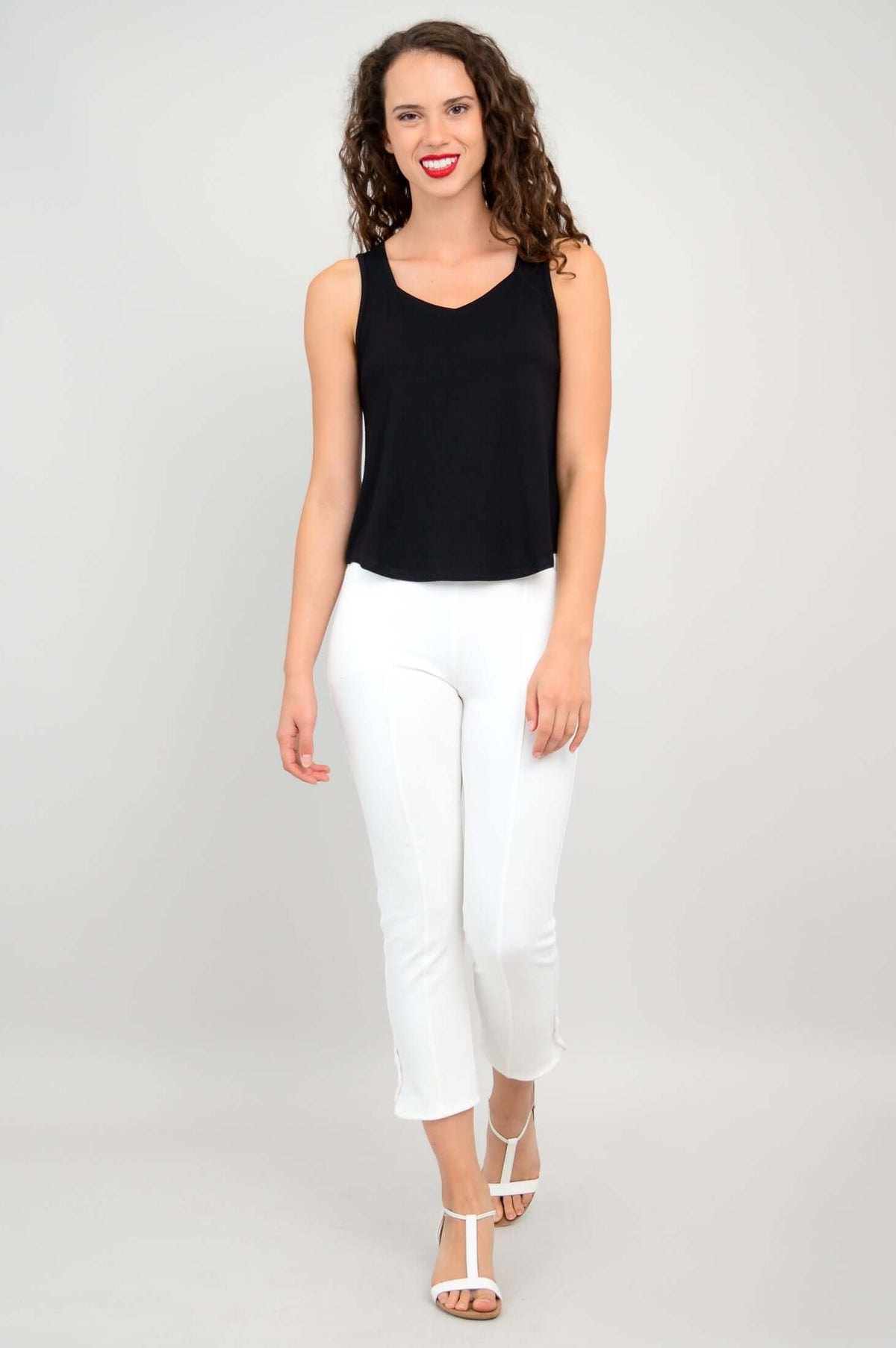 Woman walking forward in black tank top and white pants, front view