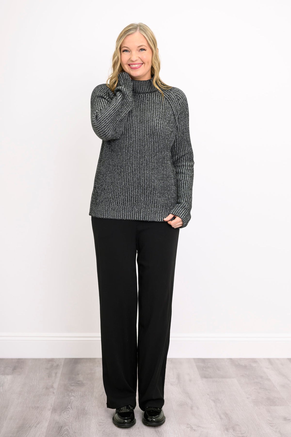 Smiling woman posing in a dark gray mock neck sweater with long sleeves, showing a casual front-facing look.