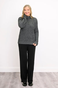 Smiling woman posing in a dark gray mock neck sweater with long sleeves, showing a casual front-facing look.