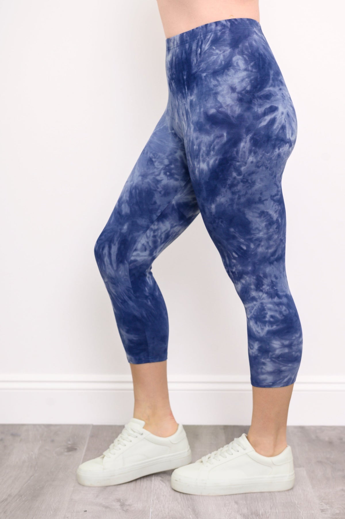 Side view of woman modeling her blue tie-dye capri leggings featuring an elastic waistband