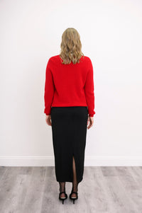 Three quarter angled shot of a woman modeling a red wool blend cardigan with red pearl button detail.