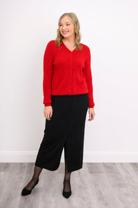 front view of a model in a vibrant red ribbed hem v-neck cardigan sweater and black skirt.