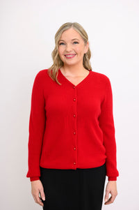 Studio portrait of a smiling woman modeling a bright red long sleeve button up sweater with a high v-neck.