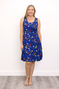 Front view of woman wearing a blue dress with red flowers and sandals against a white background