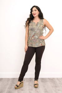 Full body view of woman looking slightly away and posing in a green floral to and brown pants