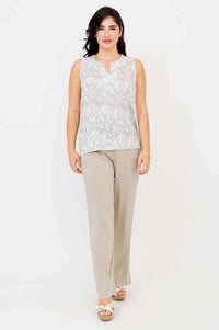 Model walking forward in Scarlette split neck tank and beige pants against white background