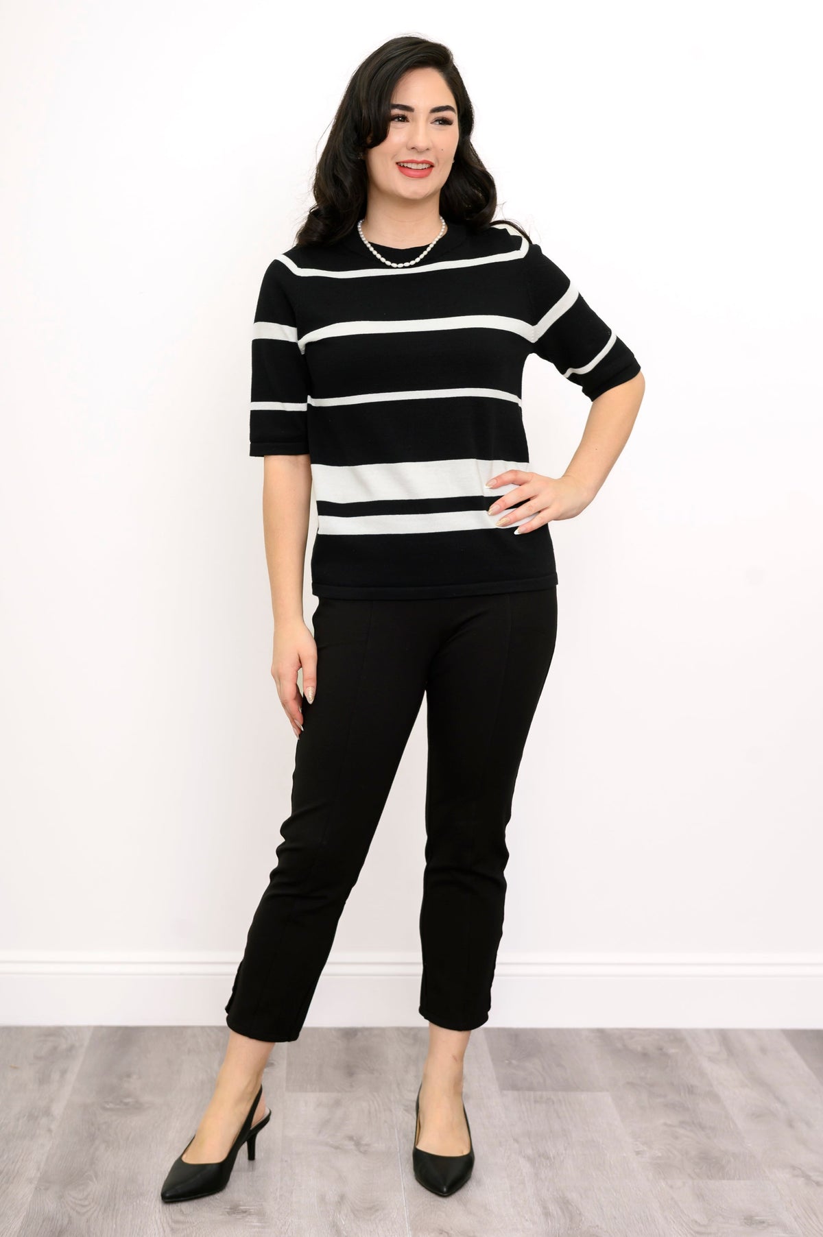 Woman posing with her hand on her hip and smiling while wearing a striped sweater