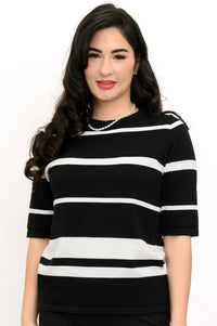 Close up view of woman wearing a black an white striped sweater and pearl necklace
