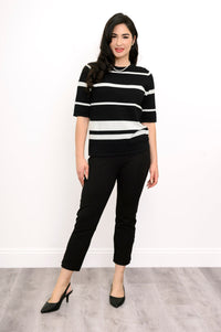 Full body view of woman posing in a black and white outfit and black heels